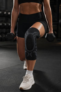 Rodillera Kneeva negra en uso durante entrenamiento en gimnasio, vista frontal